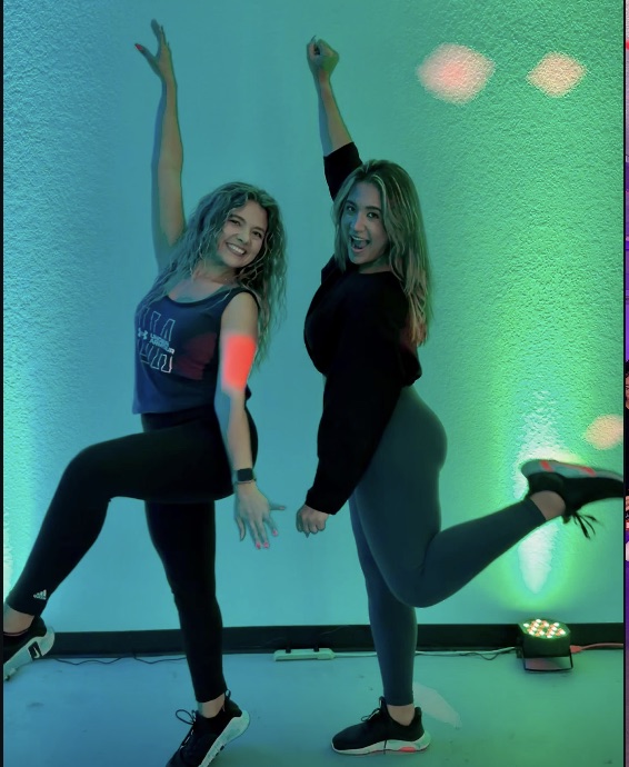 Two Enough7Fitness dancers striking a pose, arms raised